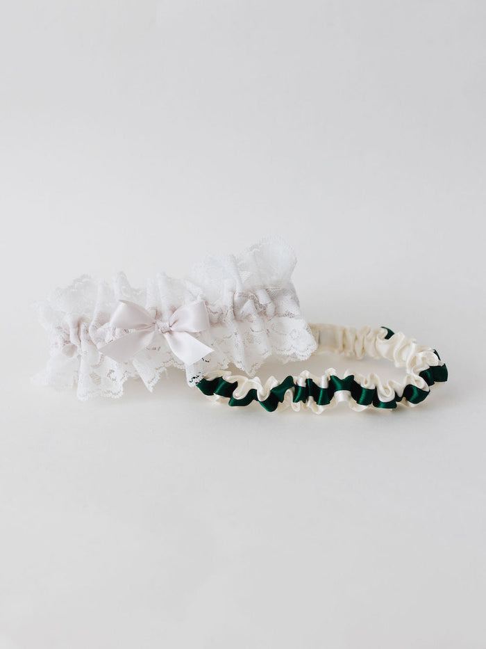 two personalized wedding garters with ivory satin and a green satin ribbon and ivory lace with a blush pink satin bow handmade by The Garter Girl