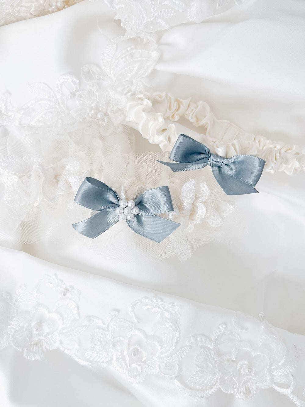 Custom wedding garter set made from the bride's mother's wedding dress lace, pearls and tulle with something blue satin bow handmade by top wedding garter heirloom designer, The Garter Girl