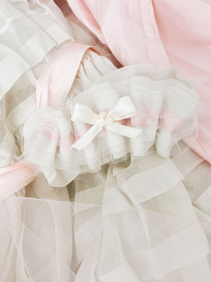 a beautiful custom ivory tulle and satin wedding garter made with pink satin and buttons from bride's mother and grandmother's dress and finished with a short ivory bow handmade by The Garter Girl