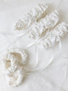 wedding garter heirlooms with white lace from mom's wedding dress and white satin details and bow alongside scrunchies made from mother of the bride's dress materials handmade by The Garter Girl
