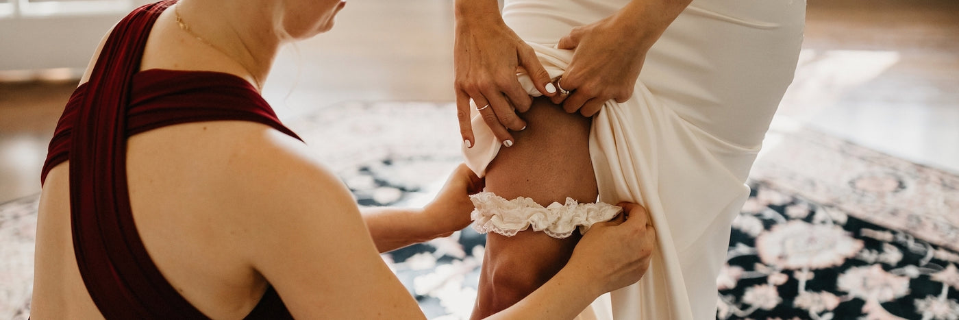 bridesmaid helping bride put on family heirloom garter