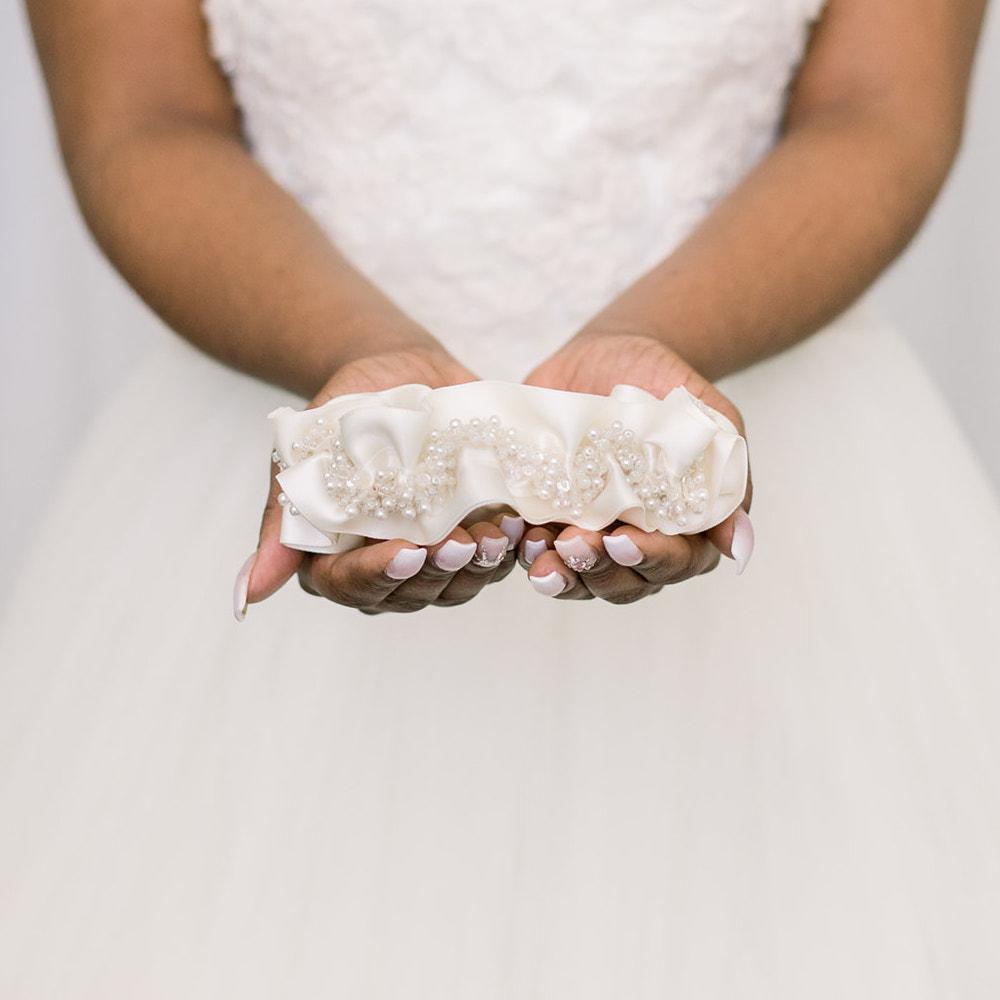 Shop our heirloom bridal garter with faux pearls, beads and ivory satin.