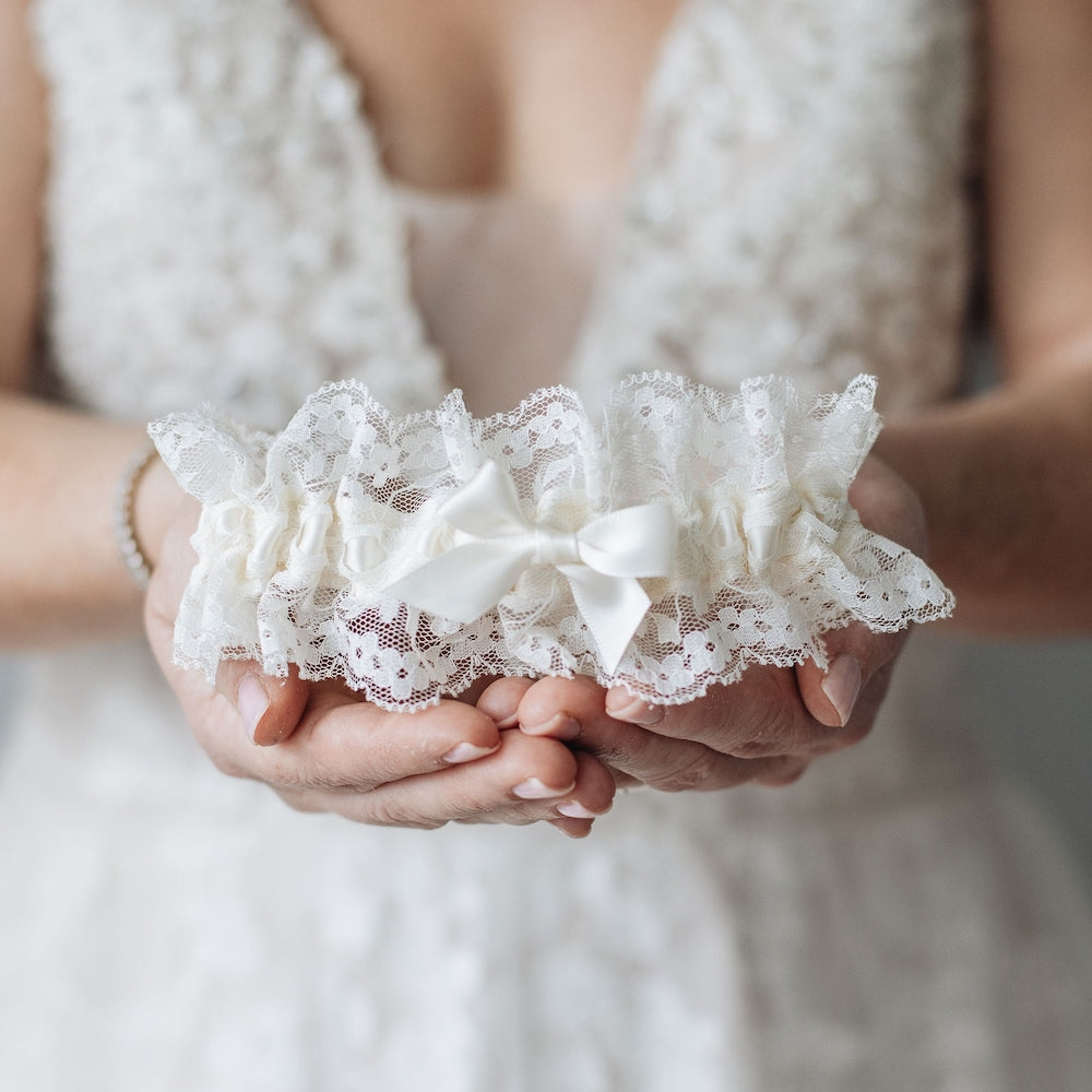 Shop our heirloom wedding garter with floral ivory lace and satin bow.
