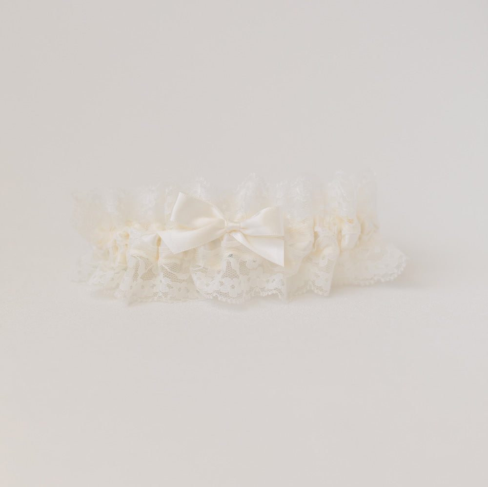 Shop our heirloom wedding garter with floral ivory lace and satin bow.